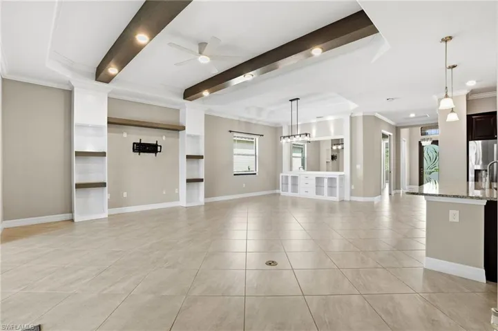 Unfurnished living and dining room with crown molding, ceiling fan, recessed lighting, light tile patterned flooring, and beamed ceiling