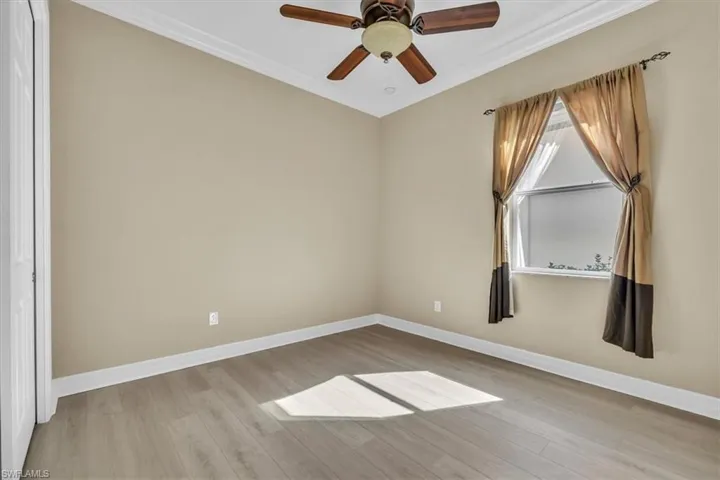 Unfurnished room with ornamental molding, light wood-style flooring, and ceiling fan