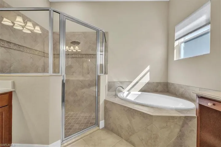 Bathroom with vanity, a garden tub, a shower stall, and tile patterned flooring