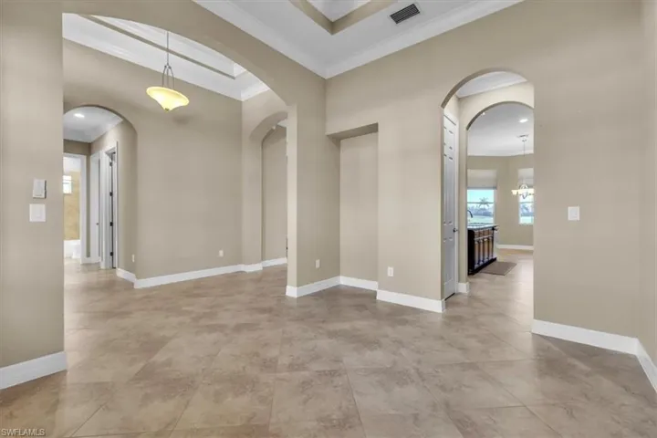 Empty room featuring ornamental molding and arched walkways