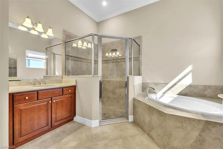 Full bath with a garden tub, vanity, ornamental molding, a shower stall, and light tile patterned flooring