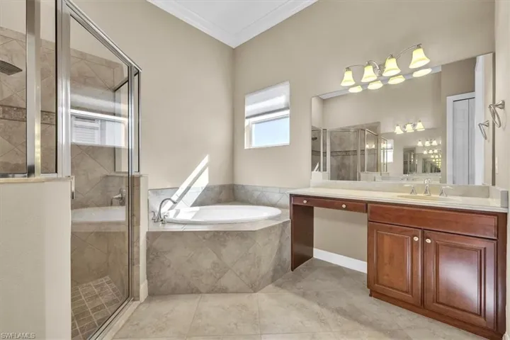 Full bathroom featuring a shower stall, a bath, vanity, and crown molding