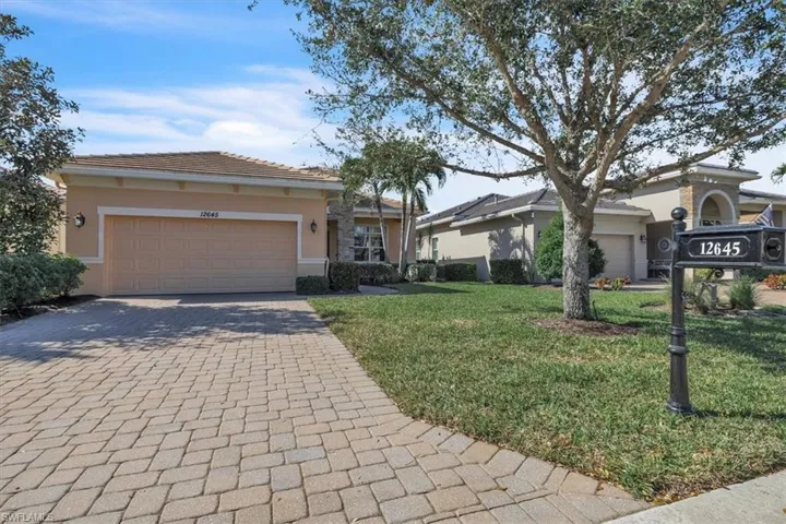 View of front of home with a front lawn, decorative driveway, stucco siding, a garage, and a tiled roof