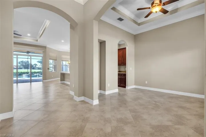 Spare room featuring a ceiling fan, a tray ceiling, ornamental molding, recessed lighting, and arched walkways