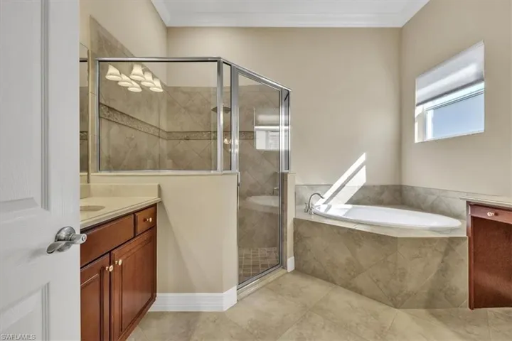 Full bath with vanity, a garden tub, a shower stall, ornamental molding, and light tile patterned floors