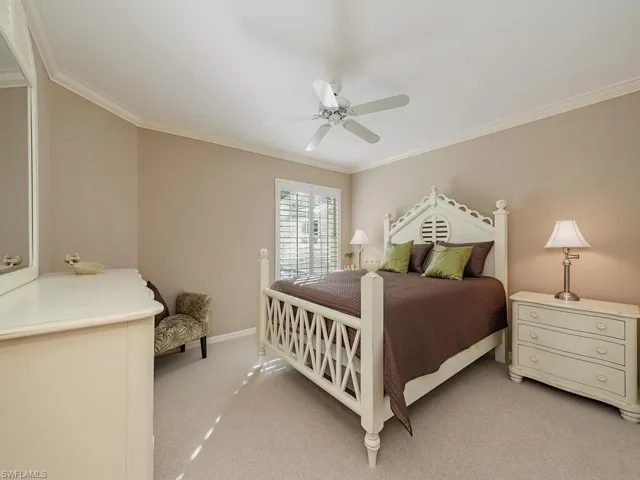 Bedroom 2 featuring light colored carpet, ceiling fan, and ornamental molding