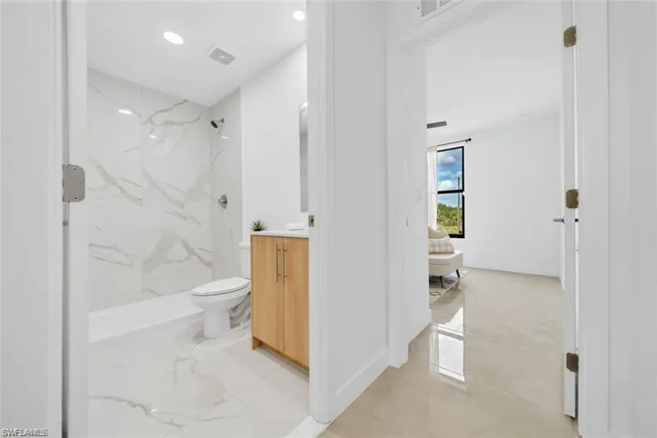 Bathroom with a marble finish shower, visible vents, vanity, and toilet