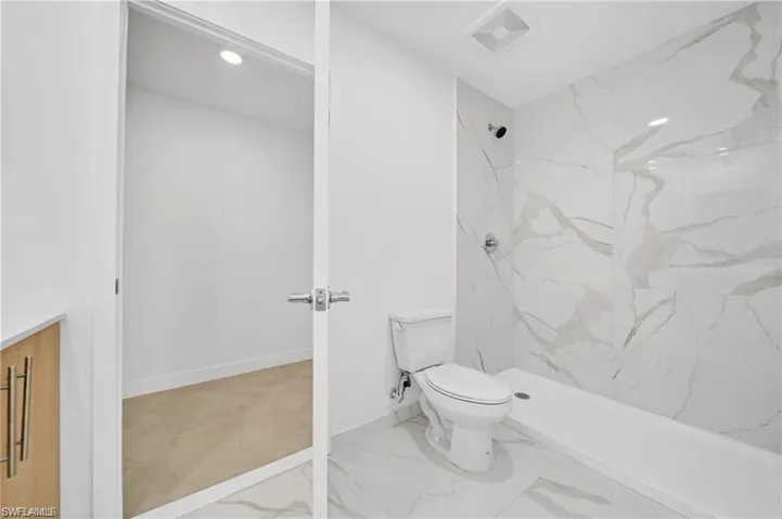 Full bathroom featuring toilet, marble finish floor, vanity, a marble finish shower, and visible vents