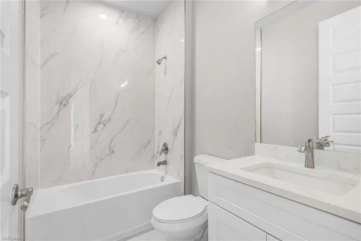 Full bath featuring vanity, a textured wall, and shower / washtub combination