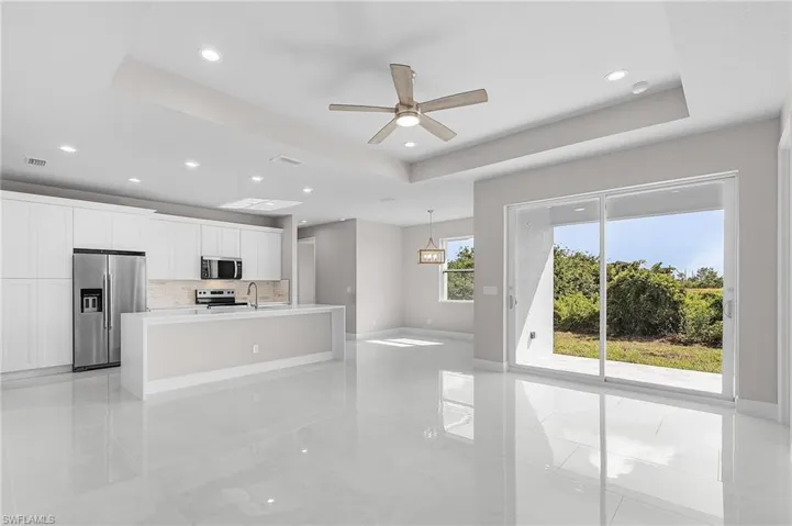 Kitchen featuring a tray ceiling, appliances with stainless steel finishes, white cabinetry, ceiling fan, and recessed lighting