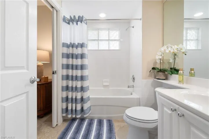 This first level bathroom is accessible from the bedroom or the den. It has a toilet, a single sink, a tub, and a shower.