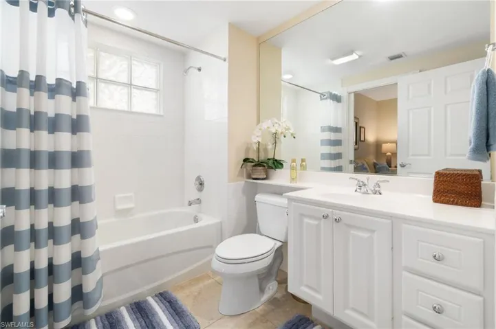 This first level bathroom is accessible from the bedroom or the den. It has a toilet, a single sink, a tub, and a shower.