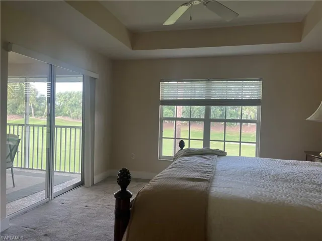 Bedroom with ceiling fan, access to exterior, a raised ceiling, and carpet floors
