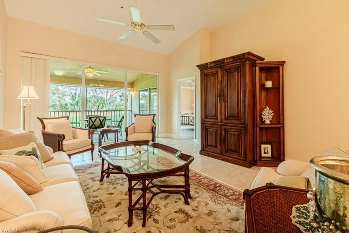 Living room with ceiling fan, high vaulted ceiling, and light tile patterned flooring