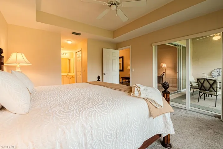 Carpeted bedroom featuring access to exterior, a raised ceiling, and ceiling fan