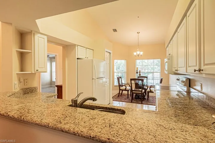 Kitchen featuring tile patterned floors, sink, pendant lighting, an inviting chandelier, and white appliances