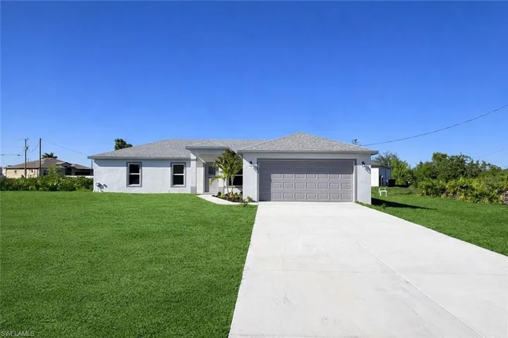 View of front facade with a front lawn, stucco siding, driveway, a garage, and a shingled roof