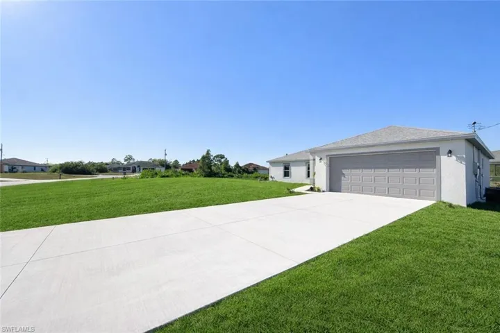 View of front of house with a front lawn, stucco siding, concrete driveway, and an attached garage