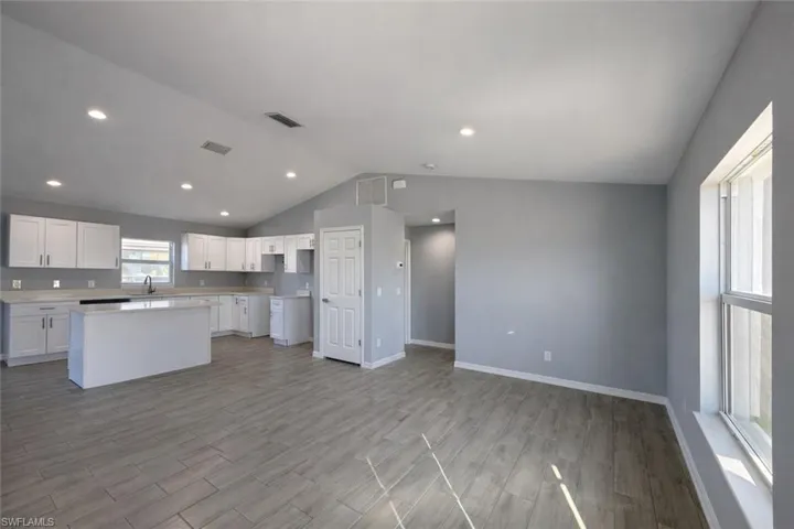 Kitchen with white cabinets, a center island, light countertops, light wood-style floors, and open floor plan