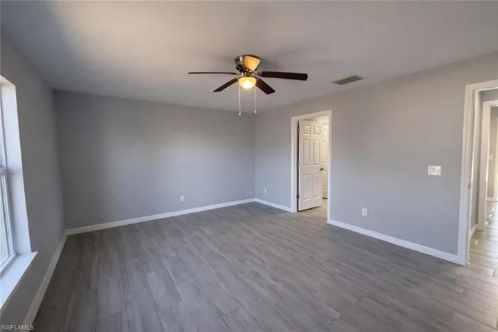 Unfurnished room featuring dark wood-style flooring and ceiling fan