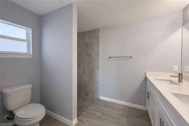 Full bathroom with a walk in shower, double vanity, and wood finish floors