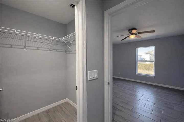 Walk in closet featuring wood finish floors and a ceiling fan