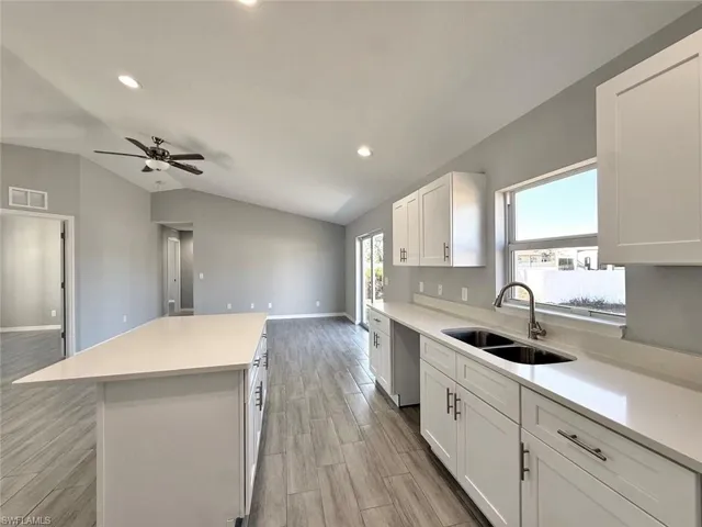 Kitchen featuring white cabinets, a kitchen island, wood tiled floors, open floor plan, and recessed lighting