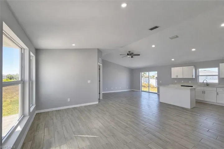 Kitchen with white cabinets, open floor plan, wood tiled floors, a ceiling fan, and lofted ceiling