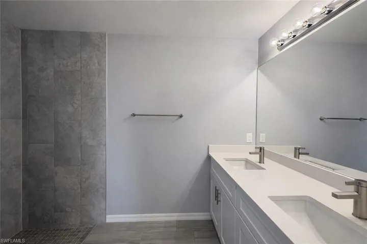 Full bath with double vanity and a tile shower