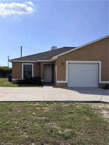 Ranch-style house with stucco siding, driveway, a garage, a front lawn, and a shingled roof