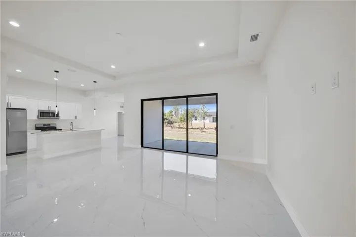 Unfurnished living room featuring light marble finish floors, a tray ceiling, and recessed lighting