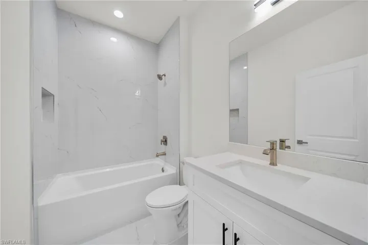 Bathroom featuring vanity, shower / bathtub combination, and recessed lighting