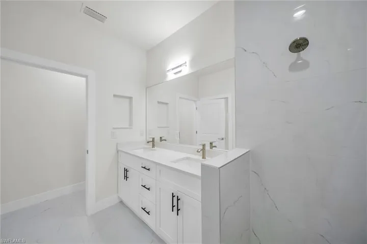 Full bath with double vanity and light marble finish floors