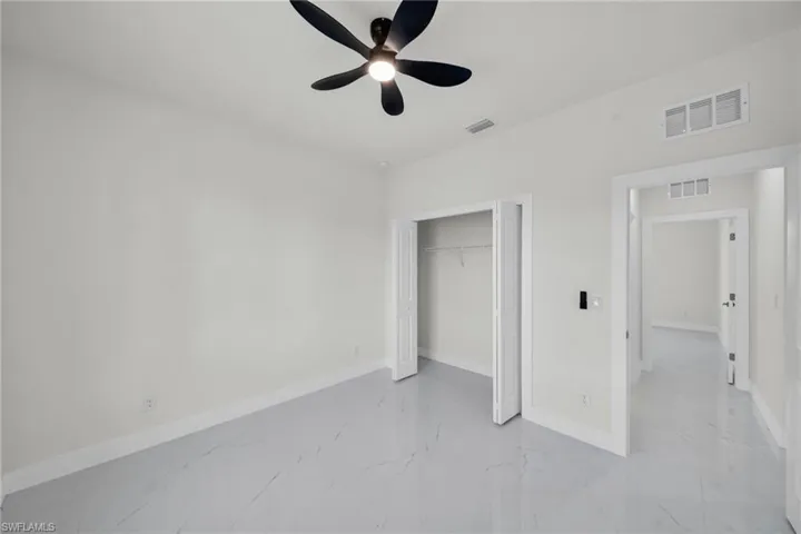 Unfurnished bedroom featuring a closet, ceiling fan, and light marble finish flooring