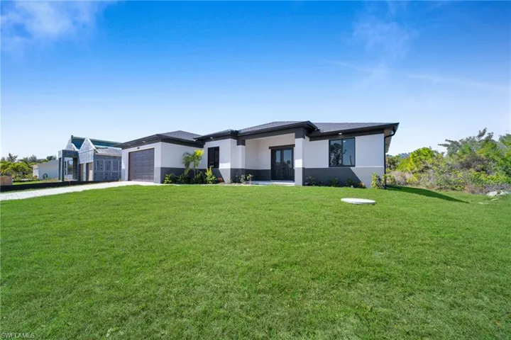 Prairie-style home with a front lawn, stucco siding, and concrete driveway
