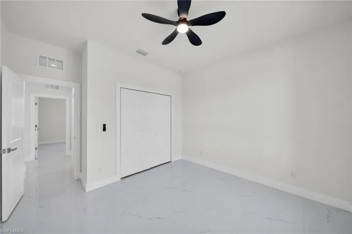 Unfurnished bedroom with a ceiling fan, a closet, and light marble finish floors