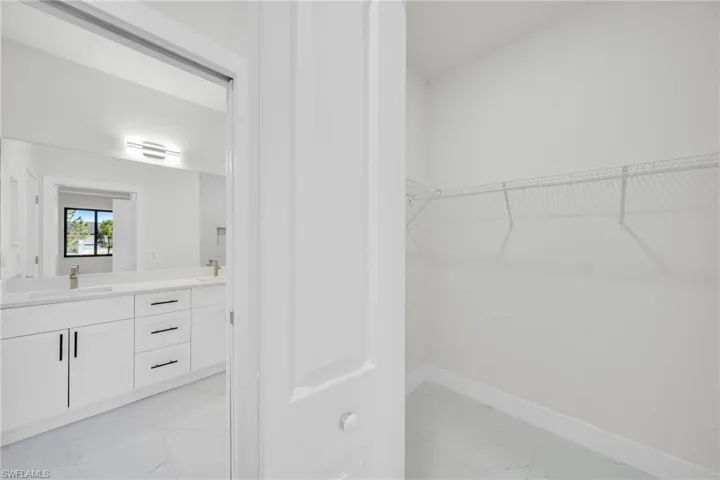 Walk in closet featuring light marble finish flooring