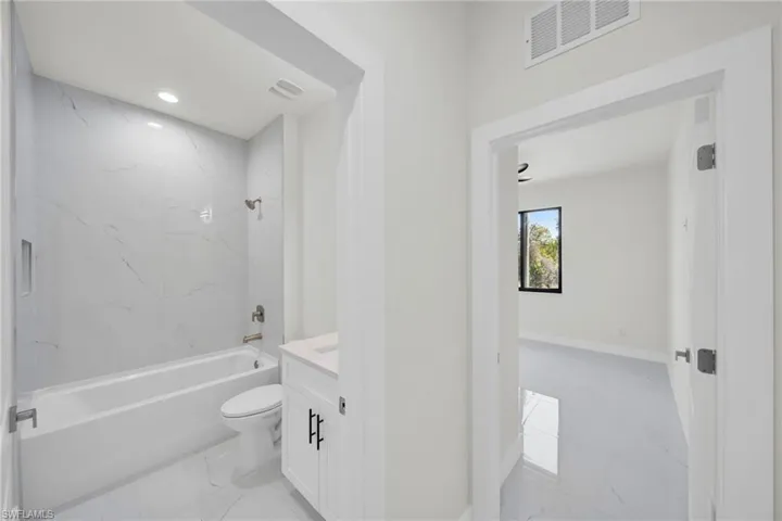 Full bath with light marble finish flooring, vanity, bathing tub / shower combination, and recessed lighting