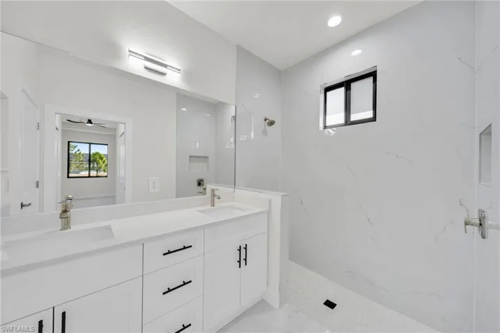 Full bathroom with plenty of natural light, double vanity, a marble finish shower, and recessed lighting
