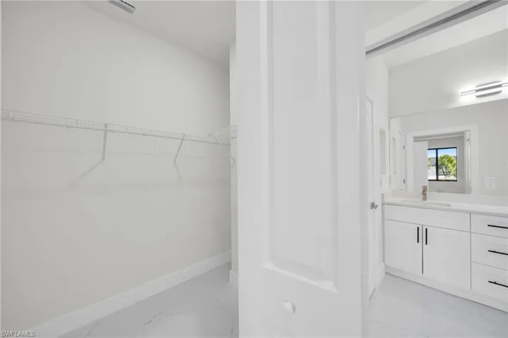 Walk in closet featuring light marble finish flooring and a sink