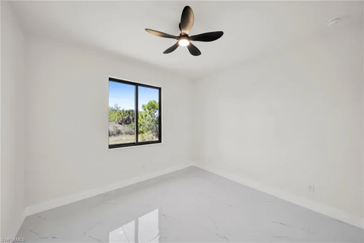Unfurnished room with light marble finish floors and ceiling fan