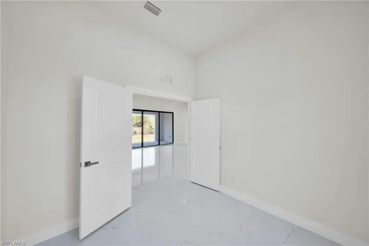 Spare room featuring light marble finish flooring and lofted ceiling