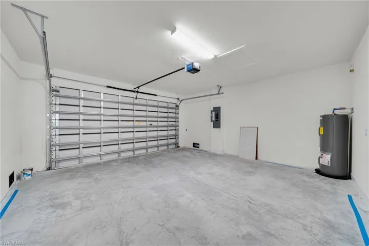 Garage featuring water heater, electric panel, and a garage door opener