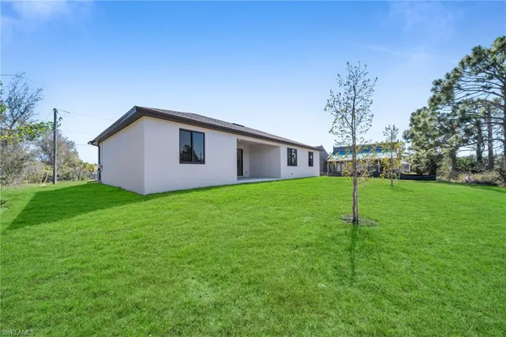 Rear view of house featuring a yard, a patio area, and stucco siding