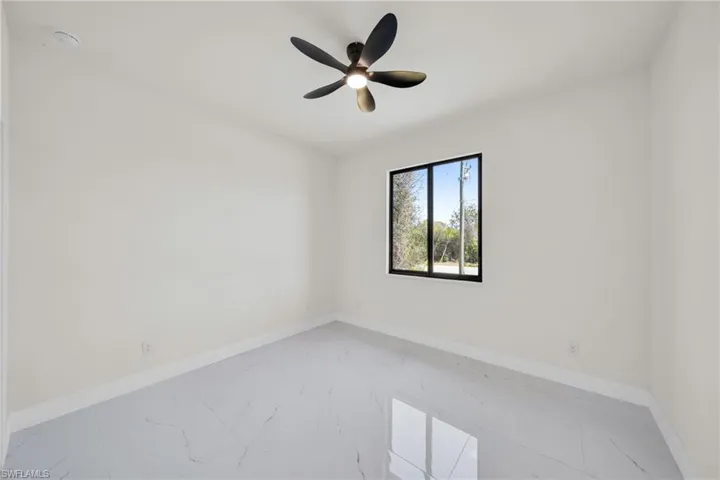 Empty room featuring marble finish floors and a ceiling fan