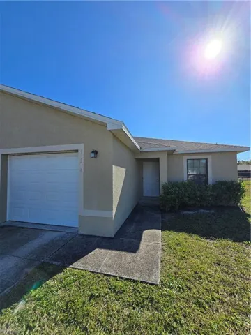 Single story home featuring stucco siding, a front lawn, and an attached garage