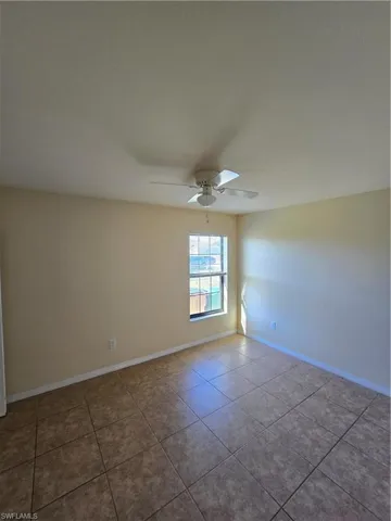 Empty room featuring tile patterned floors and a ceiling fan