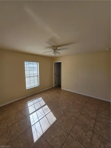 Tiled empty room with baseboards and a ceiling fan