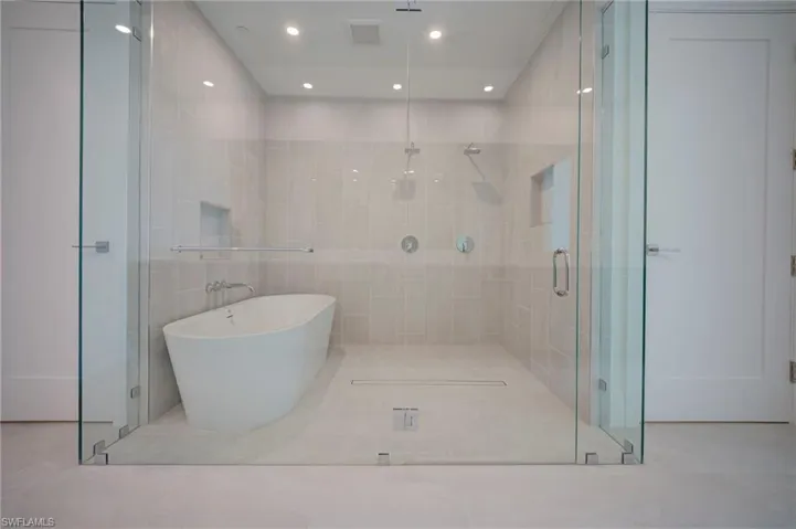 Full bathroom featuring a soaking tub, a stall shower, tile walls, light tile patterned flooring, and recessed lighting