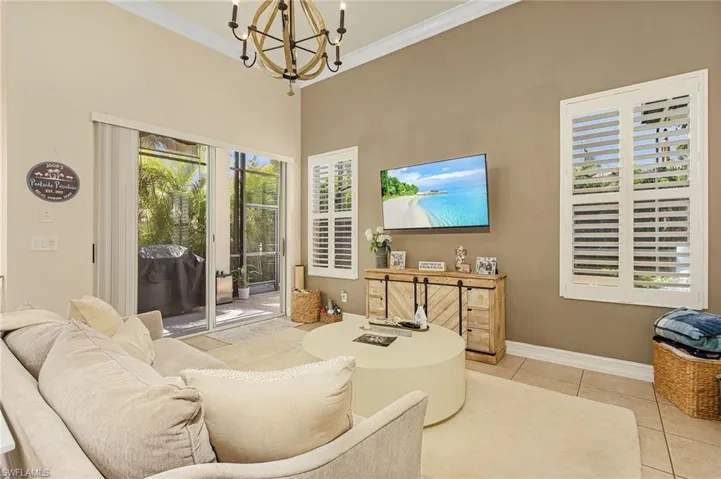 Living room featuring a chandelier, light tile flooring, and crown molding